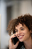 Young adult woman listening to voice mail on smart phone