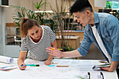 Architekten diskutieren über einen Bauplan, während sie sich auf einen Tisch stützen