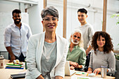 Agency manager sitting on table while looking at the camera