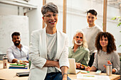 Agency manager sitting on table while looking at the camera