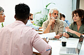 Businesswomen and businessmen discussing while gathered at office