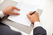 High angle view close up of male real estate agent signing a contract during meeting