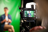 Blick über die Schulter auf eine professionelle Videokamera, die ein Interview filmt