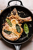 Pork chops with butter and sage in a pan