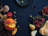 Fall food ingredients on dark blue background with copy space. Flat-lay of autumn vegetables, berries and mushrooms from local market. Vegan ingredients