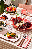 A picnic with salad at an outdoor table, with fresh fruit and fried food, on a striped table cloth