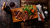 Grilled beef striploin steak with rocket salad and red wine on a dark background