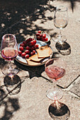 Gläser mit rosafarbenem Wein und Weintrauben im Hintergrund