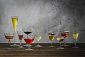 Verschiedene Cocktail-, Wein- und Sektgläser auf einem Holztisch arrangiert
