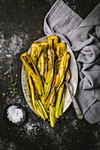 Braised leeks with wine sauce and thyme on silver platter with sea salt and gray linen cloth