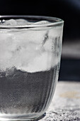 Nahaufnahme eines Glases mit reinem Wasser und Eiswürfeln an einem heißen Sommertag