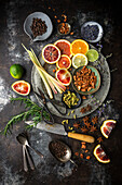 Flat arrangement of colourful citrus slices, lemongrass, herbs and spices on a dark background. Ingredients for homemade tonic water for cocktails