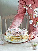 Krepptorte oder Blini-Torte für Osterfest, rosa Hintergrund, Mandelblüten, rosa Hintergrund, Frauenhände