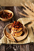 Apple and cinnamon pancake stack on wooden surface and sage green background