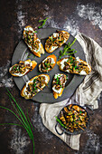 Mushroom and goat cheese crostini arranged on a pewter plate, with mushrooms in small dish