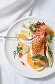 Sliced salmon fish steak on a plate of vegetables