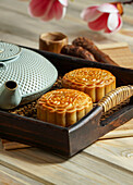 Mooncake for Mid-Autumn Festival, concept of traditional festive chinese food on an Asian wooden tray with teapot