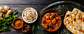 Chicken tikka masala spicy curry meat food with rice and naan bread on dark background