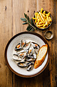 Mussels with cream cheese sauce and French fries on a wooden base