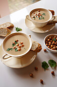 Vegane Suppe aus Blumenkohl, Kreuzkümmel und Limabohnen auf weißem Marmortisch, Großaufnahme
