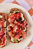 Ricotta- und Parmaschinken-Toast mit Balsamico-Nieselregen und Kresse auf einem gekachelten Hintergrund