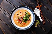 Tom Yam kung Spicy Thai soup with prawns, seafood, coconut milk and chilli peppers in a bowl