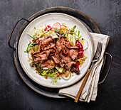Salad with roast beef and vegetables on a dark background