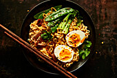 Egg and vegetable noodles in a bowl with chopsticks