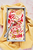 Raspberry Ripple Ice Cream Tub WIth Pistachio on Pink Background with Yellow Napkin