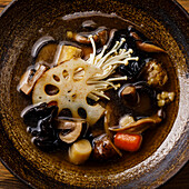 Heilende Suppe mit Wurzeln, Pilzen und Gerste auf Holztisch Hintergrund