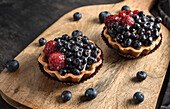 Pastries baskets with blueberries and raspberries. Cakes on a cutting board.