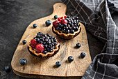 Pastries baskets with blueberries and raspberries. Cakes on a cutting board.