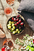 Winterliche Picknickszene mit Weintrauben und Roséwein auf einer Decke