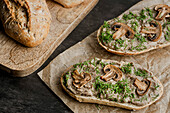 Sandwiches with mushroom pate and mushrooms on kraft paper. Bread on a cutting board.