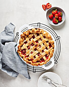 Veganer Erdbeer-Rhabarber-Kuchen mit frischen Erdbeeren auf hellem Hintergrund