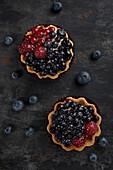 Pastry basket with blueberries and raspberries. Cake on a dark background. View from above