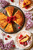 Slices of raspberry and desiccated coconut tart served on plates with fresh raspberry garnish.