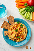 Chickpea hummus and galettes on a blue plate. View from above