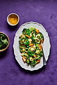 Green pea, cucumber, potato and tomato salad on a purple background with dressing