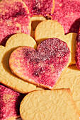 Punched out heart biscuits with pink sugar on a pink marble background