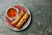 Spring rolls with sauce on stone background copy space