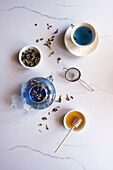 Blauer Schmetterlings-Erbsenblüten-Tee auf weißem Marmor-Hintergrund, Draufsicht, Flatlay