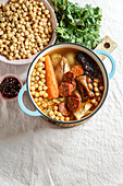 Cocido Madrileño, a traditional Spanish dish, a chickpea-based stew from Madrid with pink ceramic tiles in the background