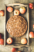 Homemade apple pie on a tray with apples