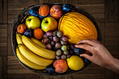 Human hand taking fruit from a basket. View from above