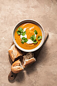 Butternut squash soup and baguette on a wooden board