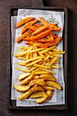 Variety of potatoes for garnish: potato wedges, french fries, sweet potato on brown background