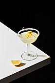 Zitronencocktail auf einem weißen Tisch und schwarzem Hintergrund