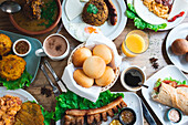 Draufsicht auf eine Reihe appetitlicher kolumbianischer Gerichte mit papas rellenas pan de bono chicharron bunuelos und caldo de costilla mit verschiedenen Getränken auf einem Holztisch in einem Restaurant