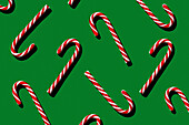 Pattern of Christmas candies cane stick on green background